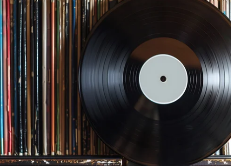 Close-up of a hand inspecting a vinyl record surface for scratches while grading